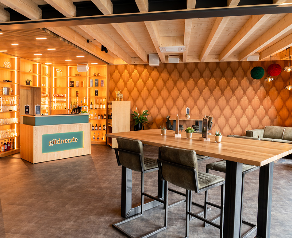 Neue Genusslounge und Fotostudio mit beleuchtetem Flaschen- und Gläserregal sowie Theke in den umgestalteten Agenturräumen.