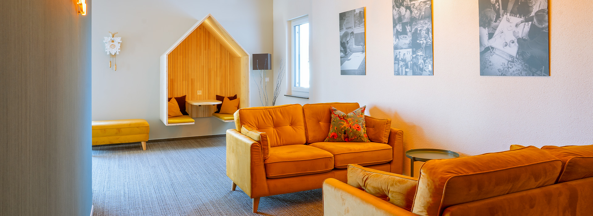 Kreativ-Lounge der Agentur mit gelben Sofas, Wandbildern und einem Besprechungsplatz in Form eines großen Vogelhauses im Hintergrund.