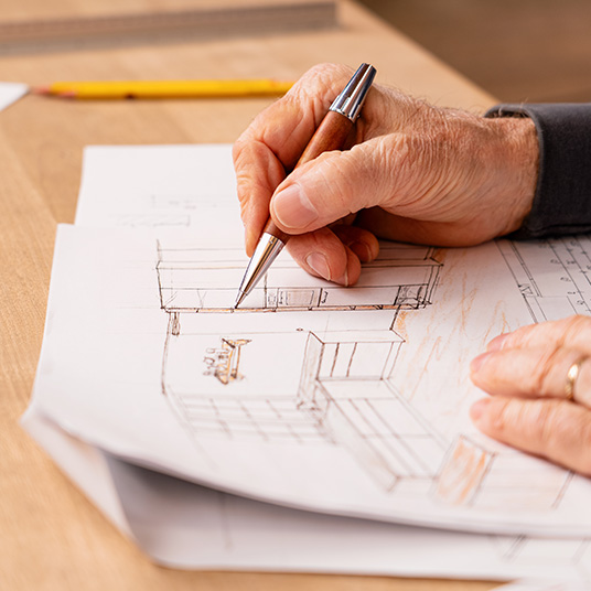 Nahaufnahme einer Hand, die eine Küchenplanung skizziert – handwerkliche Planung und individuelle Konzeptentwicklung bei Ettwein